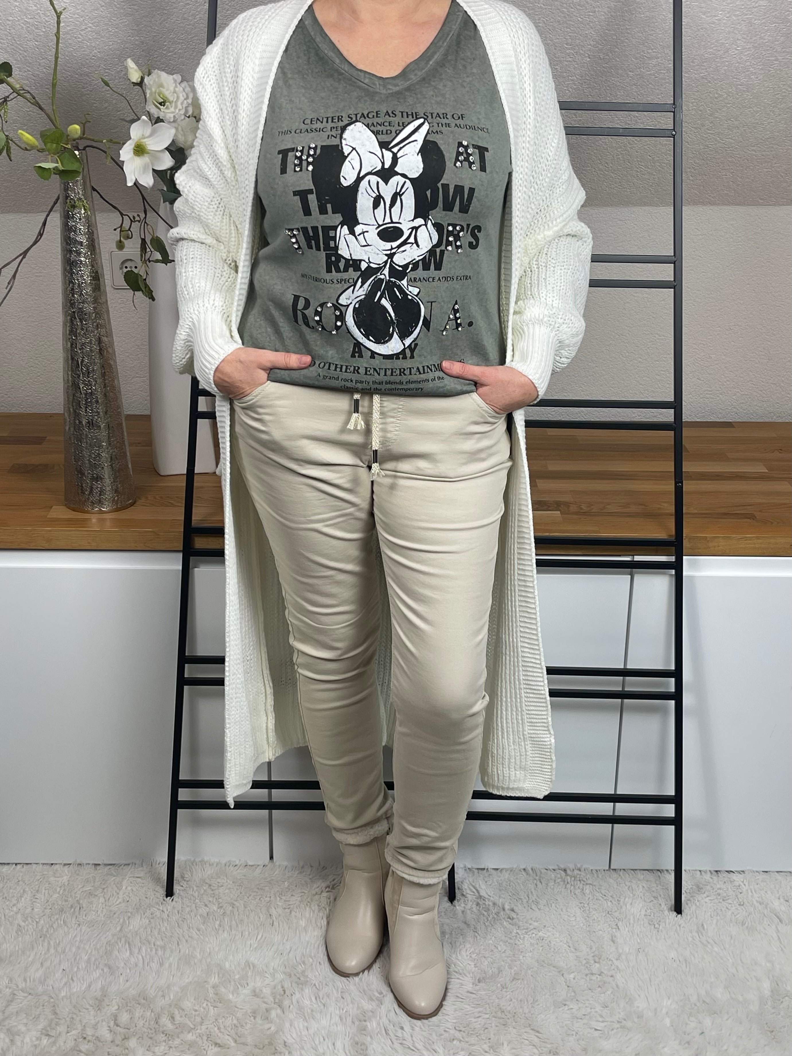 Mickey-Damenshirt langarm in khaki, aus 100 % Baumwolle mit V-Ausschnitt, Glitzer- und Pailletten-Details, kombiniert mit einem wollweißem Strickmantel, Frontansicht