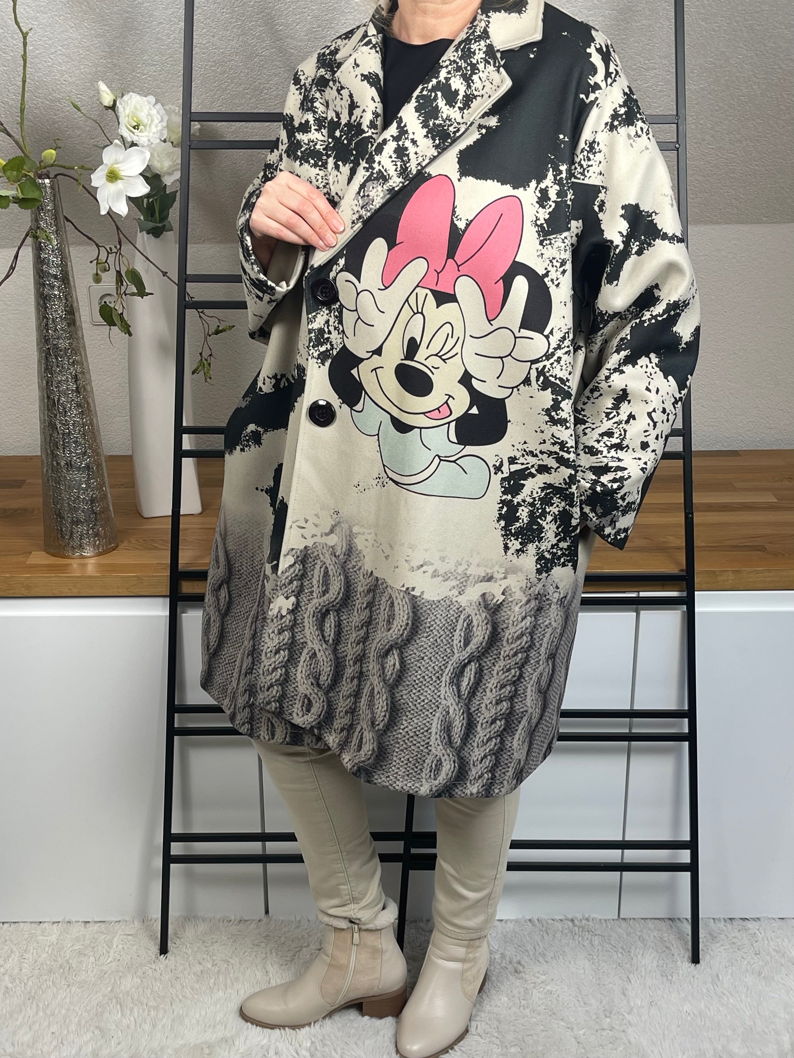 Seitliche Ansicht des „Mickey - Mouse“Oversize-Mantels aus Velour-Optik mit 50 % Wollanteil, buntem Mickey-Maus-Motiv, praktischen Taschen und schwarzen Knöpfen zum Schließen, in grau-schwarz-bunt