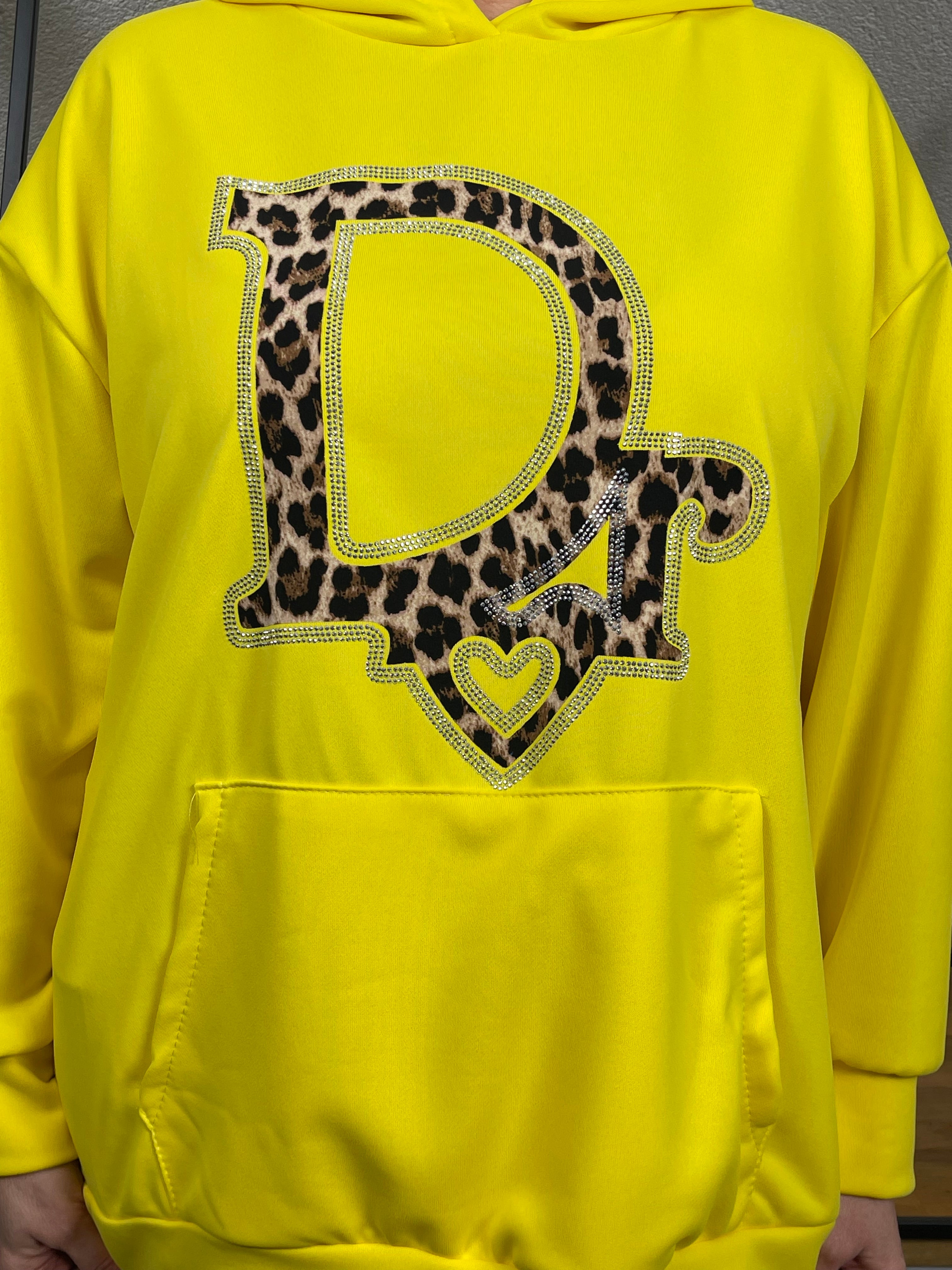 Nahaufnahme eines gelben Hoodies mit einem auffälligen Animal Print Glitzerdruck