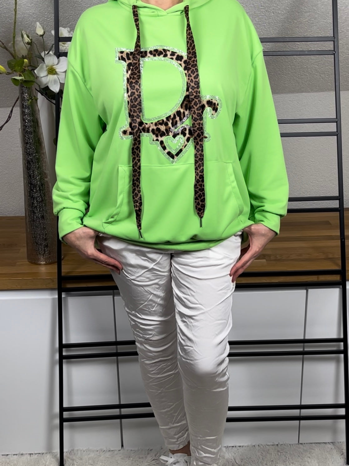 Frontansicht eines hellgrünen Hoodies mit Animal-Print und Glitzerdetails, kombiniert mit weißer Shiney - Hose