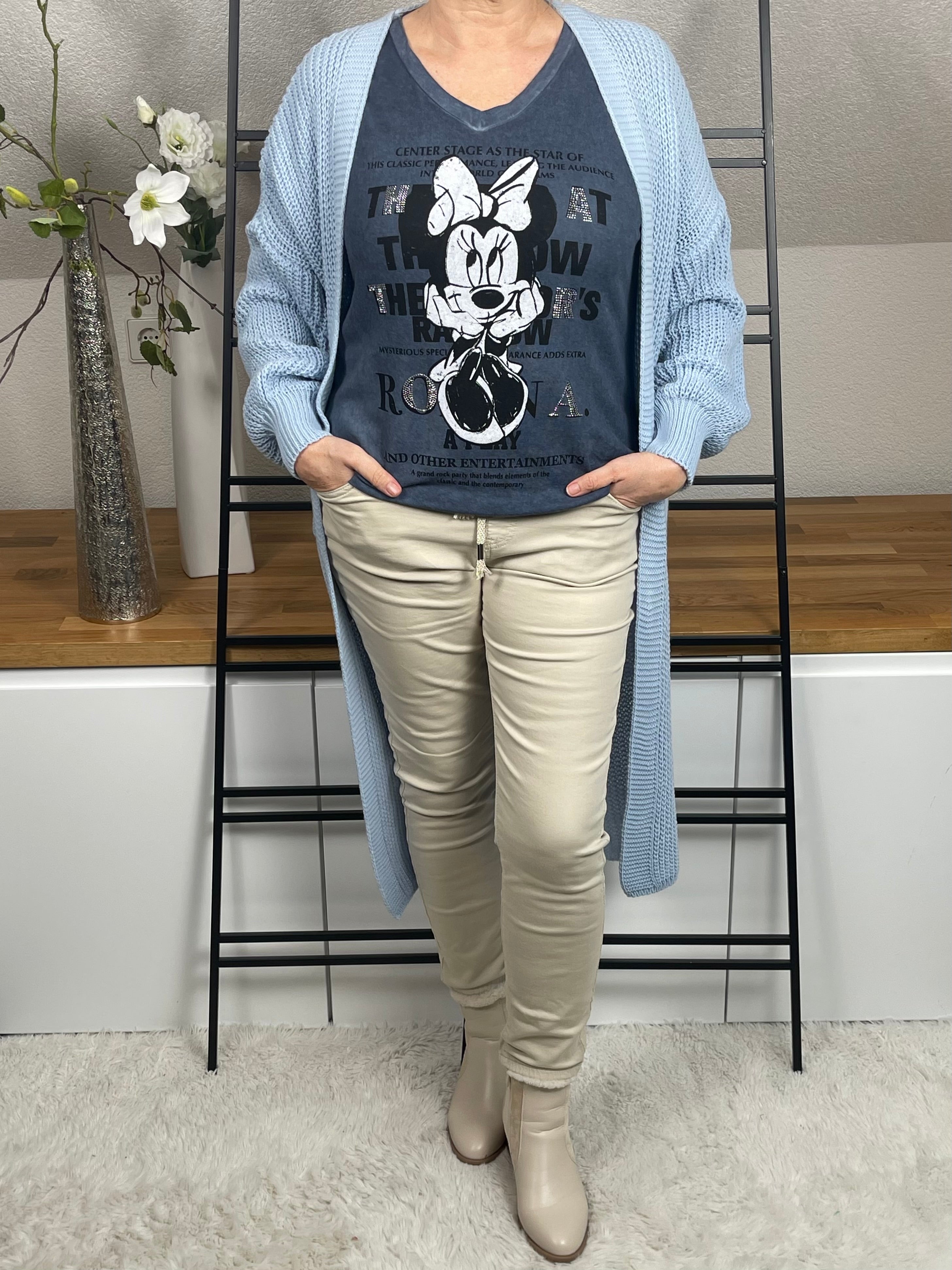 Mickey-Damenshirt langarm in jeansblau, aus 100 % Baumwolle mit V-Ausschnitt, Glitzer- und Pailletten-Details, kombiniert mit einem hellblauen Strickmantel, Frontansicht