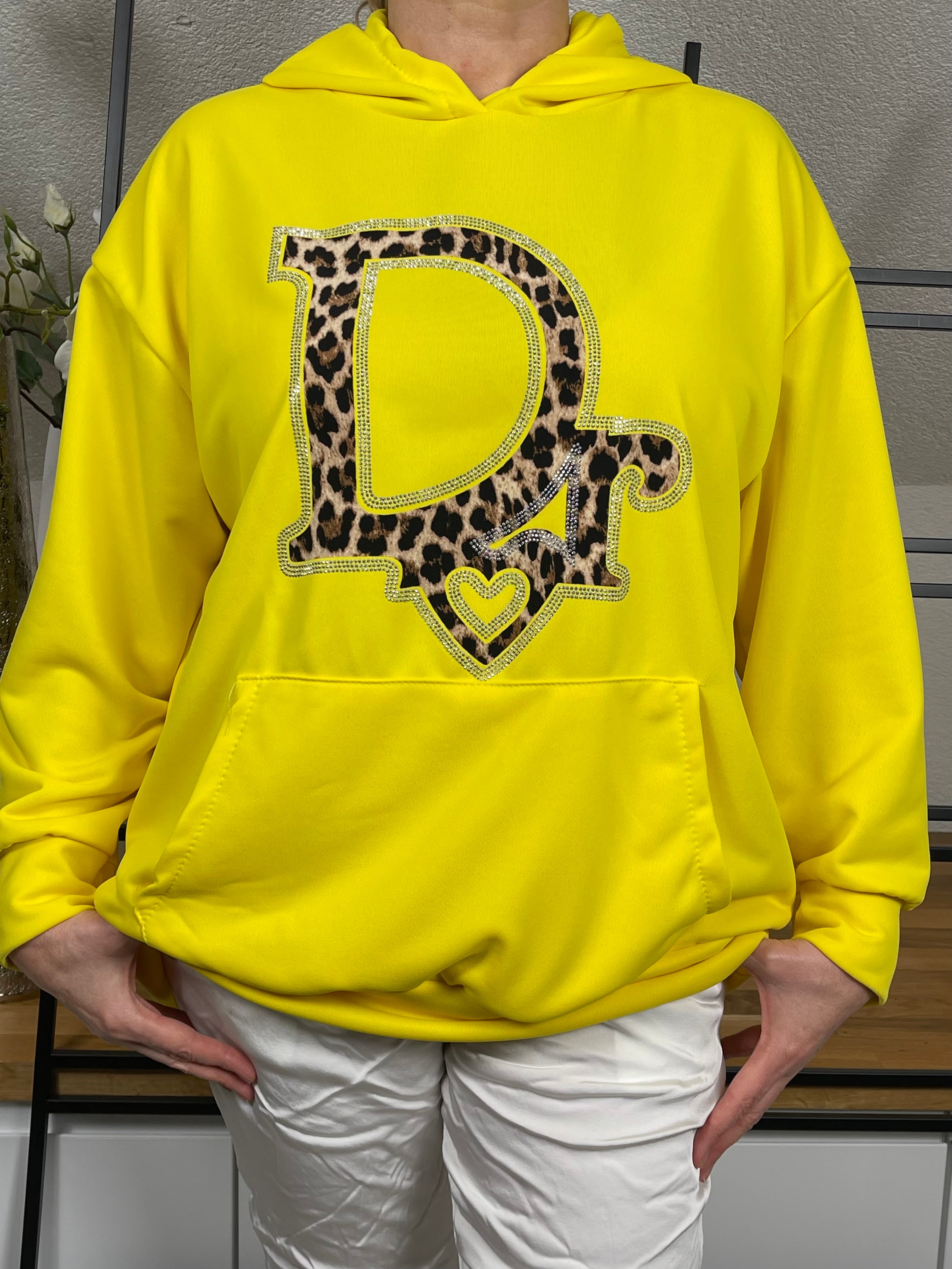 Nahaufnahme eine gelben Hoodies mit Animal Glitzer Druck und einer weißen, glänzenden Shiney Hose